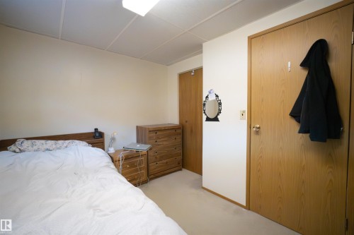 Room featuring neutral-toned carpeting and walls, suspended ceiling tiles, and a flush-mount overhead light fixture - 4724 38B Avenue Nw, Edmonton, AB - Indoor Photo Showing Bedroom