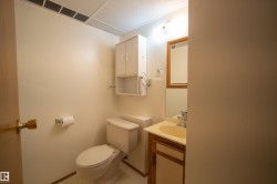 Compact bathroom featuring a neutral color palette, built-in vanity with a single sink, wood-framed mirror, and overhead cabinet storage - 
