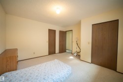 Carpeted room featuring multiple wood-finish doors and a ceiling-mounted light fixture - 