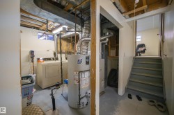 Basement utility area featuring a washer, dryer, water heater, and furnace - 