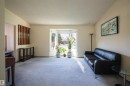Carpeted living area featuring a prominent bay window, neutral wall tones, and a decorative wood screen element - 4724 38B Avenue Nw, Edmonton, AB  - Indoor 