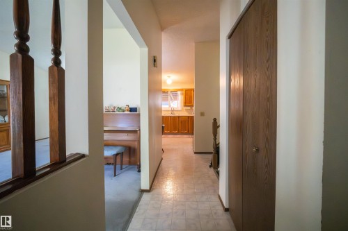Hallway featuring patterned tile flooring and a built-in wood-finish closet with bi-fold doors - 4724 38B Avenue Nw, Edmonton, AB - Indoor Photo Showing Other Room