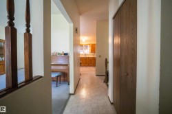 Hallway featuring patterned tile flooring and a built-in wood-finish closet with bi-fold doors - 