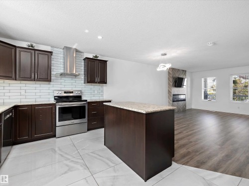 The kitchen features dark wood cabinetry, granite countertops, and a white subway tile backsplash, complemented by stainless steel appliances - 9852 217 Street, Edmonton, AB - Indoor Photo Showing Kitchen With Upgraded Kitchen
