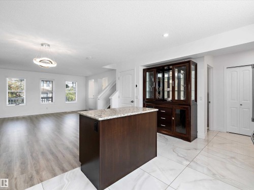The property features a bright and spacious open-concept living area with a contemporary light fixture, large windows, and light-toned flooring - 9852 217 Street, Edmonton, AB - Indoor Photo Showing Other Room