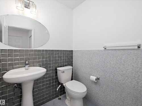 Bathroom featuring a pedestal sink, toilet, and an oval mirror - 9852 217 Street, Edmonton, AB - Indoor Photo Showing Bathroom