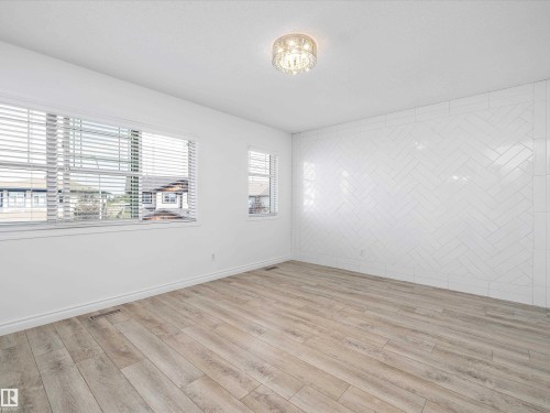 This room features light wood-style flooring, white walls, and a decorative ceiling light fixture - 9852 217 Street, Edmonton, AB - Indoor Photo Showing Other Room