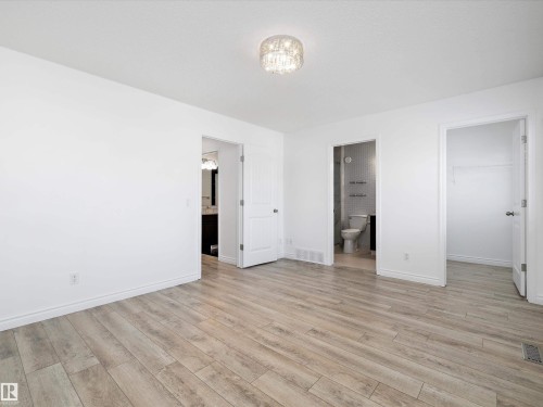 This room features light wood-style flooring, white walls, and a decorative ceiling light fixture - 9852 217 Street, Edmonton, AB - Indoor Photo Showing Other Room