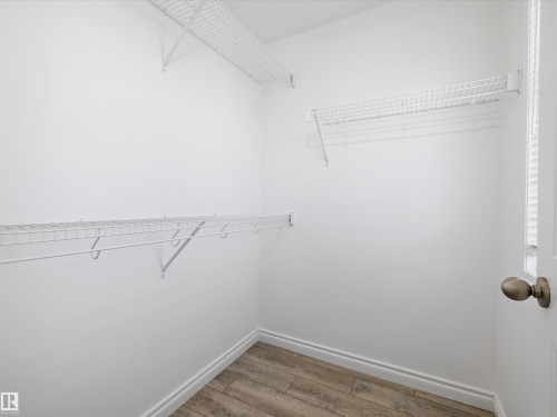 Well-appointed closet space featuring white wire shelving for organized storage and wood-look flooring - 9852 217 Street, Edmonton, AB - Indoor With Storage