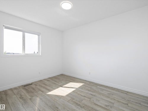 This room features light-toned flooring, white walls, and a window providing natural light - 9852 217 Street, Edmonton, AB - Indoor Photo Showing Other Room