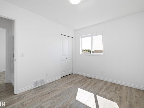 This room features light-colored plank flooring, white walls, and a window providing natural light - 9852 217 Street, Edmonton, AB - Indoor Photo Showing Other Room