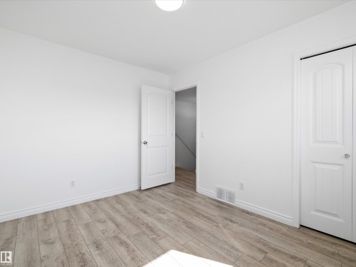 This room features light-toned wood flooring, white walls, and white trim - 9852 217 Street, Edmonton, AB - Indoor Photo Showing Other Room