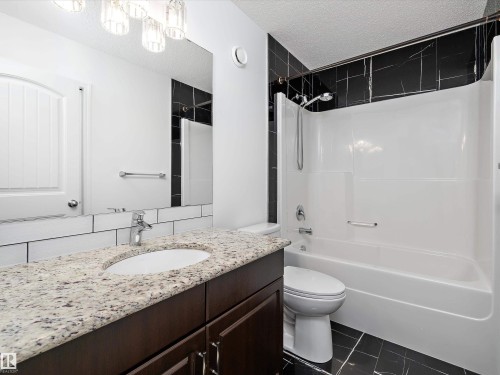 Bathroom featuring a dark wood vanity with a speckled countertop and an undermount sink - 9852 217 Street, Edmonton, AB - Indoor Photo Showing Bathroom