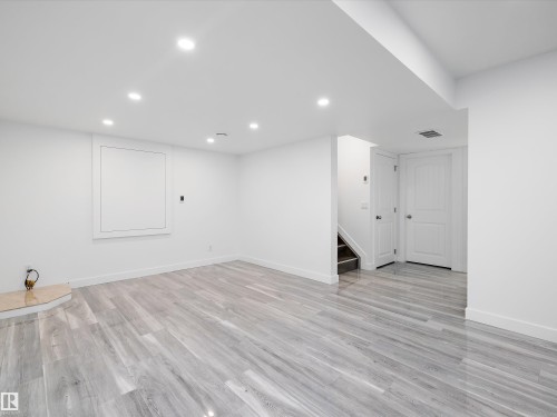 Spacious interior room with light grey wood-look flooring, white walls, and recessed lighting - 9852 217 Street, Edmonton, AB - Indoor