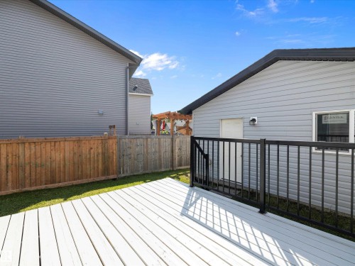 The property features a spacious deck with a black railing, a well-maintained lawn, and a wooden fence - 9852 217 Street, Edmonton, AB - Outdoor With Deck Patio Veranda With Exterior