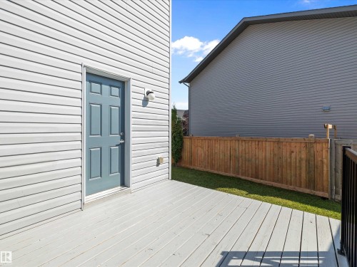 The property features a private deck, a light blue door, and white siding - 9852 217 Street, Edmonton, AB - Outdoor With Exterior