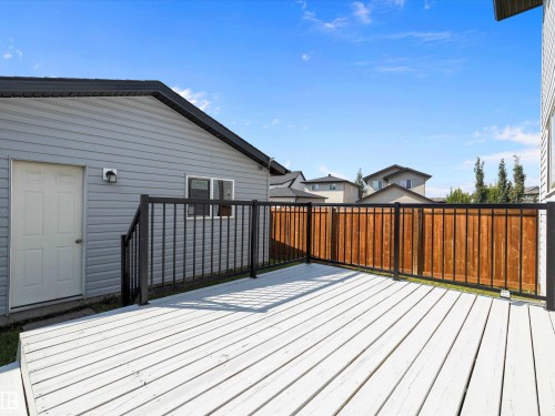 The property features a white wooden deck with black metal railings, a light gray siding exterior, and a wooden privacy fence - 9852 217 Street, Edmonton, AB - Outdoor With Deck Patio Veranda With Exterior