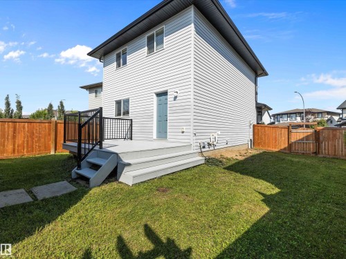 The property features a fenced backyard with a lawn and a raised deck with steps - 9852 217 Street, Edmonton, AB - Outdoor