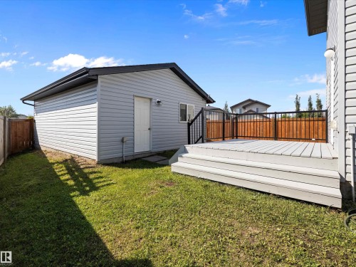 The property features a spacious deck with a black metal railing and steps leading to a grass yard - 9852 217 Street, Edmonton, AB - Outdoor With Exterior
