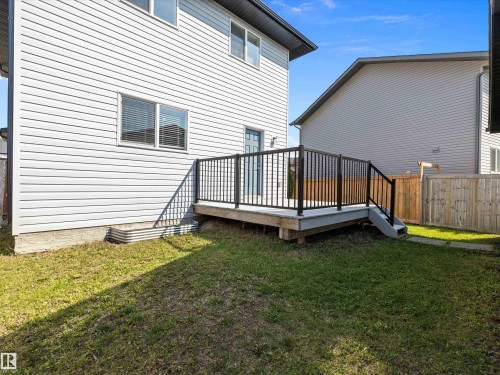 The property features a wood deck with black metal railings and a staircase leading to a grassy yard - 9852 217 Street, Edmonton, AB - Outdoor With Exterior