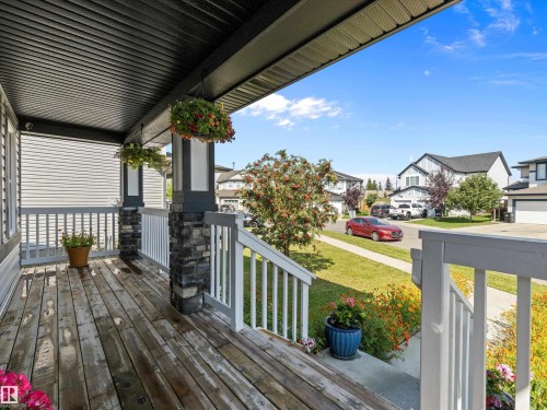 The property features a front porch with a wooden deck, white railings, and stone-accented pillars - 9852 217 Street, Edmonton, AB - Outdoor With Deck Patio Veranda With Exterior