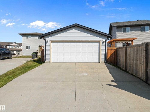 Detached garage with a paneled door, light-colored siding, and a concrete driveway - 9852 217 Street, Edmonton, AB - Outdoor With Exterior