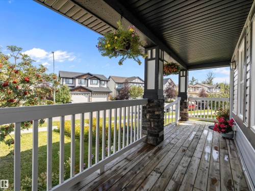 The property features a front porch with a wooden deck, white railings, and stone-accented pillars - 9852 217 Street, Edmonton, AB - Outdoor With Deck Patio Veranda With Exterior
