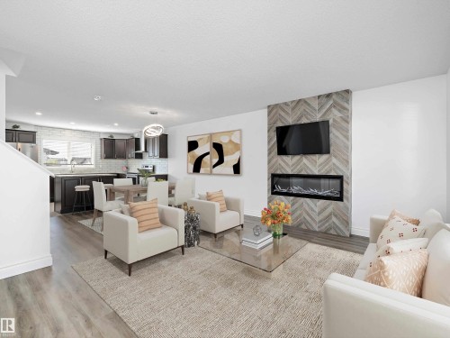 The property features an open concept living area with light-colored flooring and a decorative area rug - 9852 217 Street, Edmonton, AB - Indoor Photo Showing Living Room With Fireplace