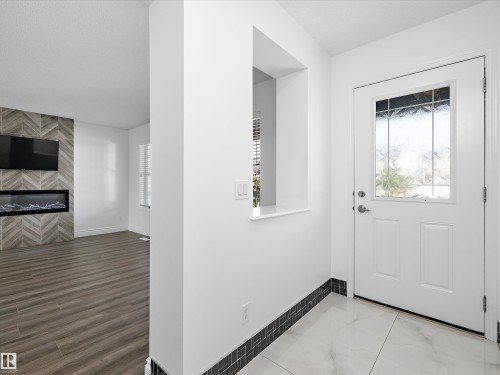 Entryway featuring a white door with a decorative window, marble-style tiled flooring, and a decorative baseboard - 9852 217 Street, Edmonton, AB - Indoor Photo Showing Other Room