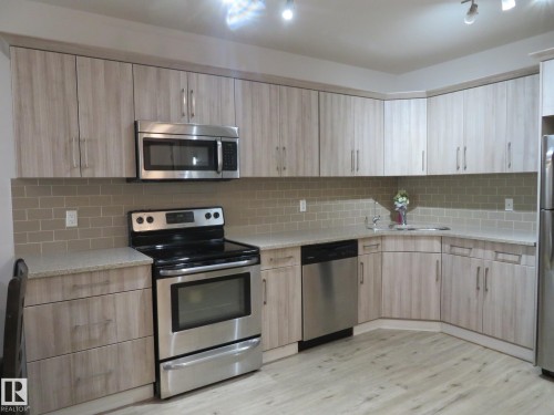 Kitchen featuring light wood-finish cabinetry, stainless steel appliances, granite-style countertops, and a subway tile backsplash - 11840B 122 Street, Edmonton, AB - Indoor Photo Showing Kitchen With Stainless Steel Kitchen