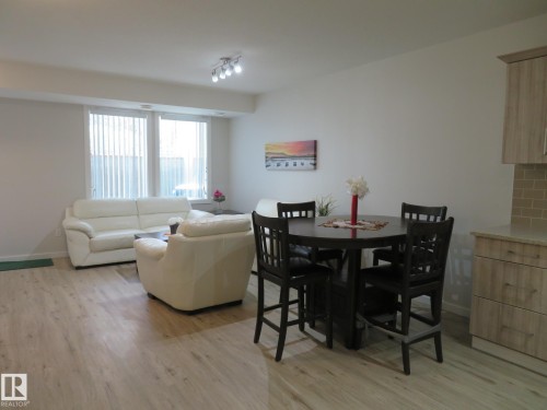 Open-concept living space featuring wood-finish flooring, recessed lighting, and large windows with vertical blinds - 11840B 122 Street, Edmonton, AB - Indoor