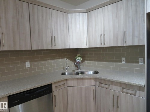 Kitchen featuring light wood-finish cabinetry with brushed nickel hardware, a stainless steel double-basin sink, and a coordinating subway tile backsplash - 11840B 122 Street, Edmonton, AB - Indoor Photo Showing Kitchen With Double Sink