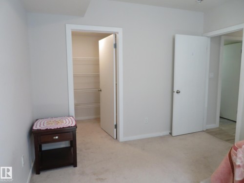 Room featuring light-colored carpet flooring, a closet with wire shelving, and neutral wall paint - 11840B 122 Street, Edmonton, AB - Indoor
