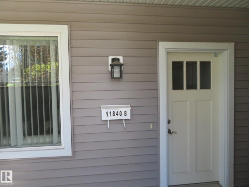 Exterior featuring horizontal siding, a white entry door with glass panels, an outdoor wall lantern, and a mail receptacle - 11840B 122 Street, Edmonton, AB - Outdoor With Exterior