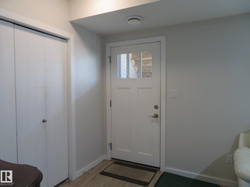 Entryway featuring a white paneled door with glass inserts, light wood-finish flooring, and a flush-mounted ceiling light - 11840B 122 Street, Edmonton, AB - Indoor Photo Showing Other Room