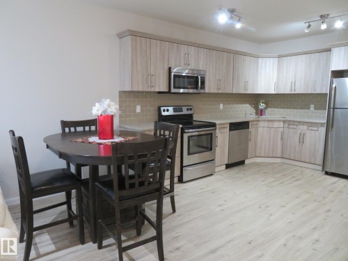 Modern kitchen featuring light wood-finish cabinetry, stainless steel appliances, a subway tile backsplash, and light-toned wood-finish flooring - 11840B 122 Street, Edmonton, AB - Indoor