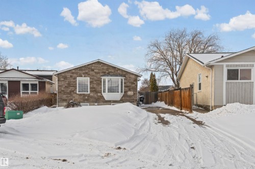 Stone facade home featuring a prominent bay window, white window trim, and a paved driveway - 115 Warwick Road, Edmonton, AB - Outdoor