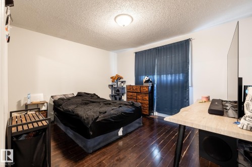 Bright interior space featuring wood-finish flooring, white wall tones, and a window with blinds and dark curtains - 3004 68 Street, Edmonton, AB - Indoor Photo Showing Bedroom