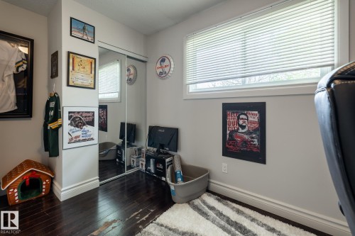 Room featuring wood-finish flooring, white baseboards, and a mirrored closet with sliding doors - 3004 68 Street, Edmonton, AB - Indoor