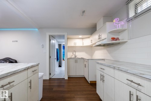 Kitchenette featuring wood-finish flooring, white subway tile backsplash, light wood-grain cabinetry, and marble-look countertops - 3004 68 Street, Edmonton, AB - Indoor Photo Showing Kitchen