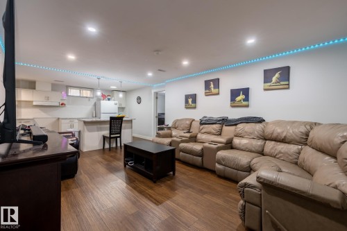 Open-concept living space featuring wood-finish flooring, recessed lighting, and a partial kitchen with white cabinetry and a breakfast bar - 3004 68 Street, Edmonton, AB - Indoor Photo Showing Living Room