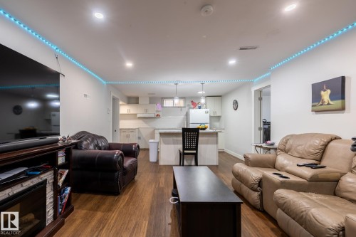 Open-concept living space featuring wood-finish flooring, recessed lighting, and a modern kitchen with a breakfast bar - 3004 68 Street, Edmonton, AB - Indoor Photo Showing Living Room With Fireplace