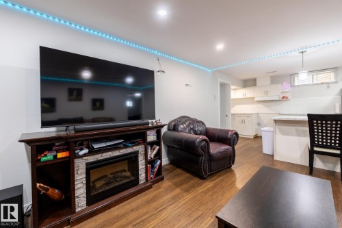 Open-concept living space featuring wood-finish flooring, recessed lighting, and a built-in media console with a stone-accented electric fireplace - 3004 68 Street, Edmonton, AB - Indoor Photo Showing Living Room With Fireplace