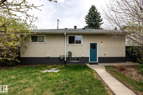 Rear exterior featuring a stucco facade, a vibrant teal entry door, and a concrete pathway - 3004 68 Street, Edmonton, AB - Outdoor