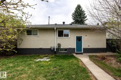 Rear exterior featuring a stucco facade, a vibrant teal entry door, and a concrete pathway - 