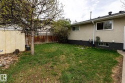 Fenced backyard featuring a mature tree, a storage shed, and a concrete patio section - 