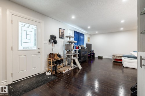 Entryway with a white paneled door featuring decorative glass, dark wood-finish flooring, recessed ceiling lighting, and white baseboards - 3004 68 Street, Edmonton, AB - Indoor Photo Showing Other Room