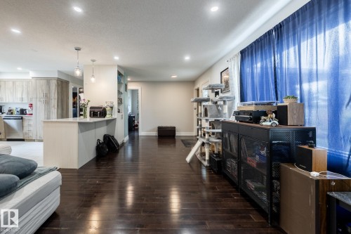 Open-concept living area featuring rich wood-finish flooring, recessed lighting, and a kitchen island with pendant lighting - 3004 68 Street, Edmonton, AB - Indoor