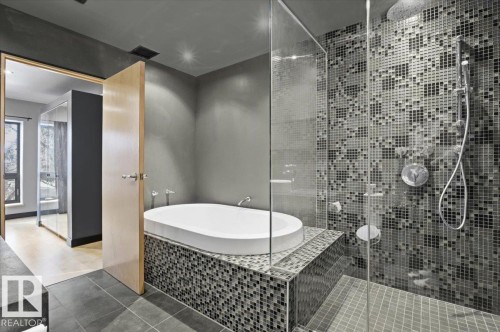Contemporary bathroom featuring a spacious walk-in shower with mosaic tile surround, a freestanding soaking tub set into a mosaic-tiled platform, and a light wood-finish door - 8709 92A Avenue, Edmonton, AB - Indoor Photo Showing Bathroom