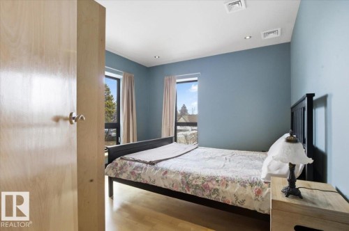 Bedroom featuring light wood-finish flooring, two large windows, recessed ceiling lighting, and a neutral wall color - 8709 92A Avenue, Edmonton, AB - Indoor Photo Showing Bedroom